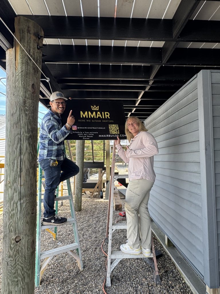 Two people repairing deck holding MMair logo